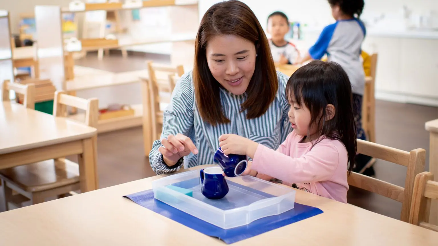 A woman and child playing with a tea set.