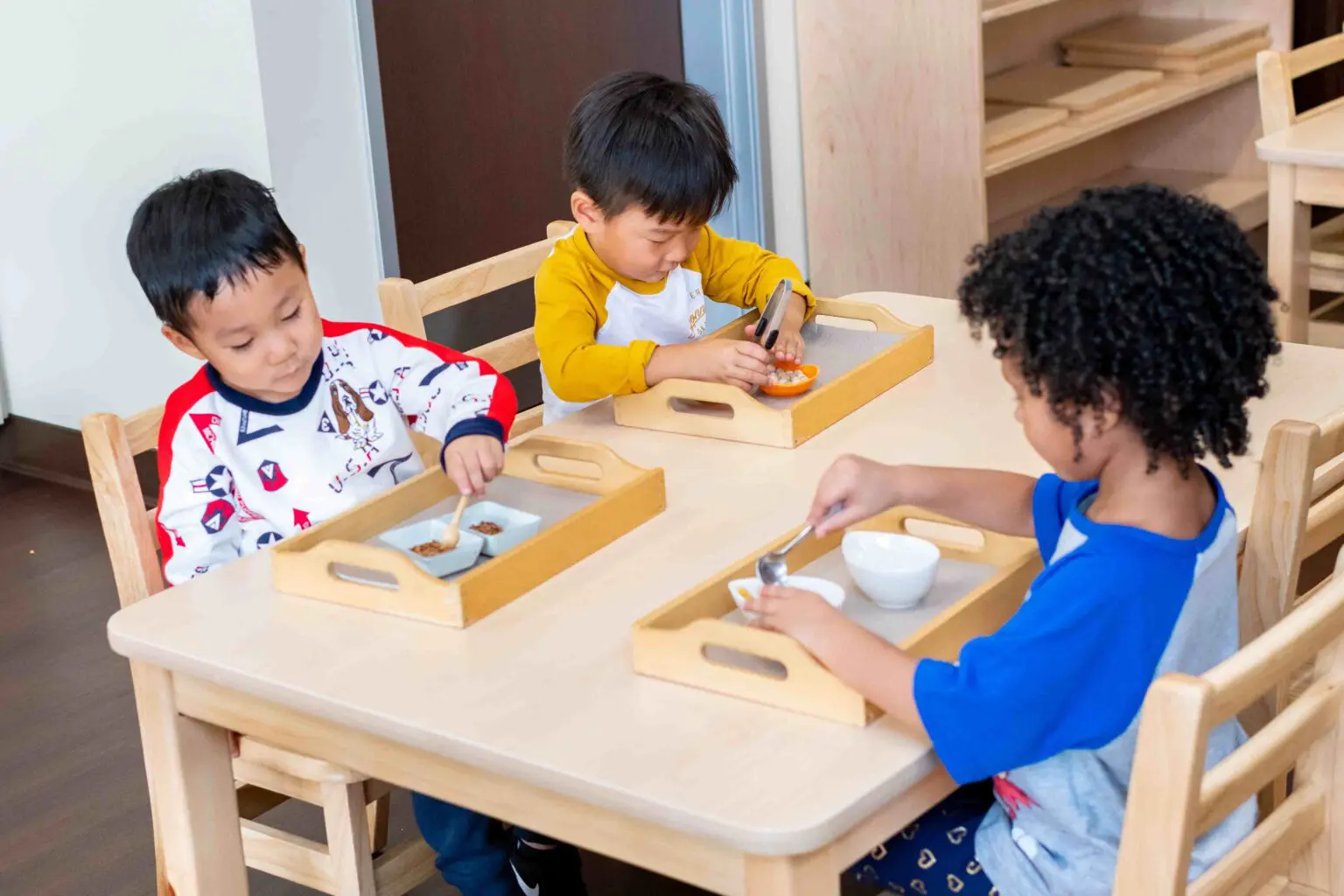 Three children are playing with a tray of food.