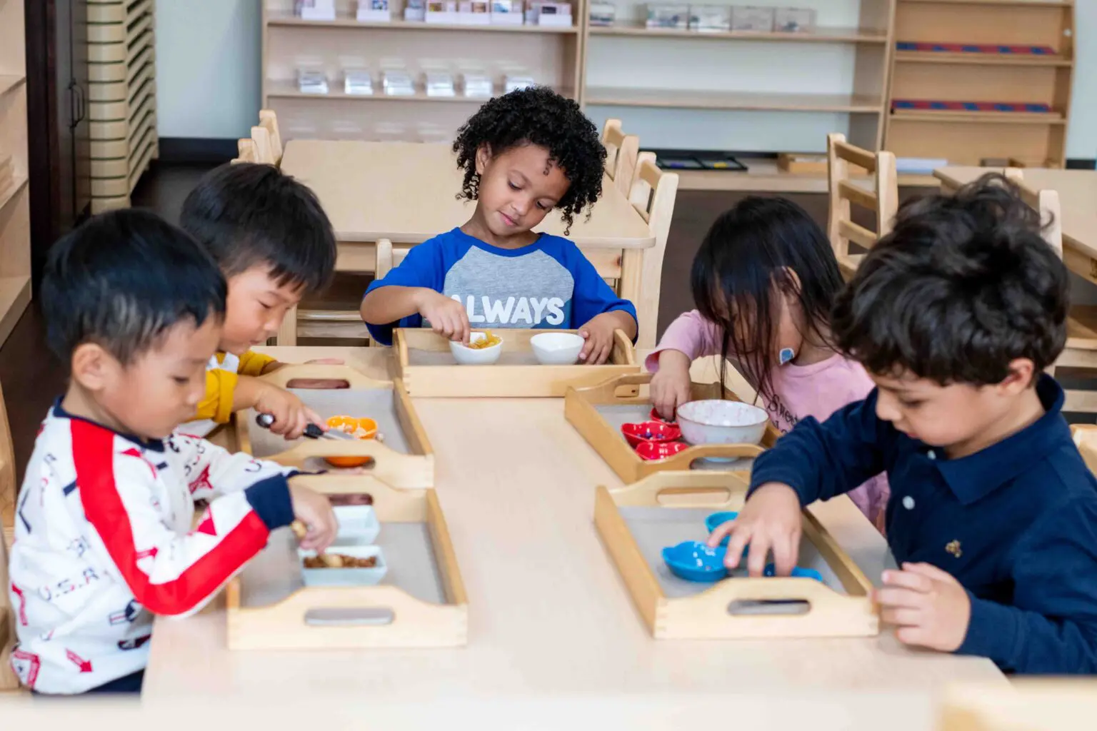 A group of children sitting at a table with trays.