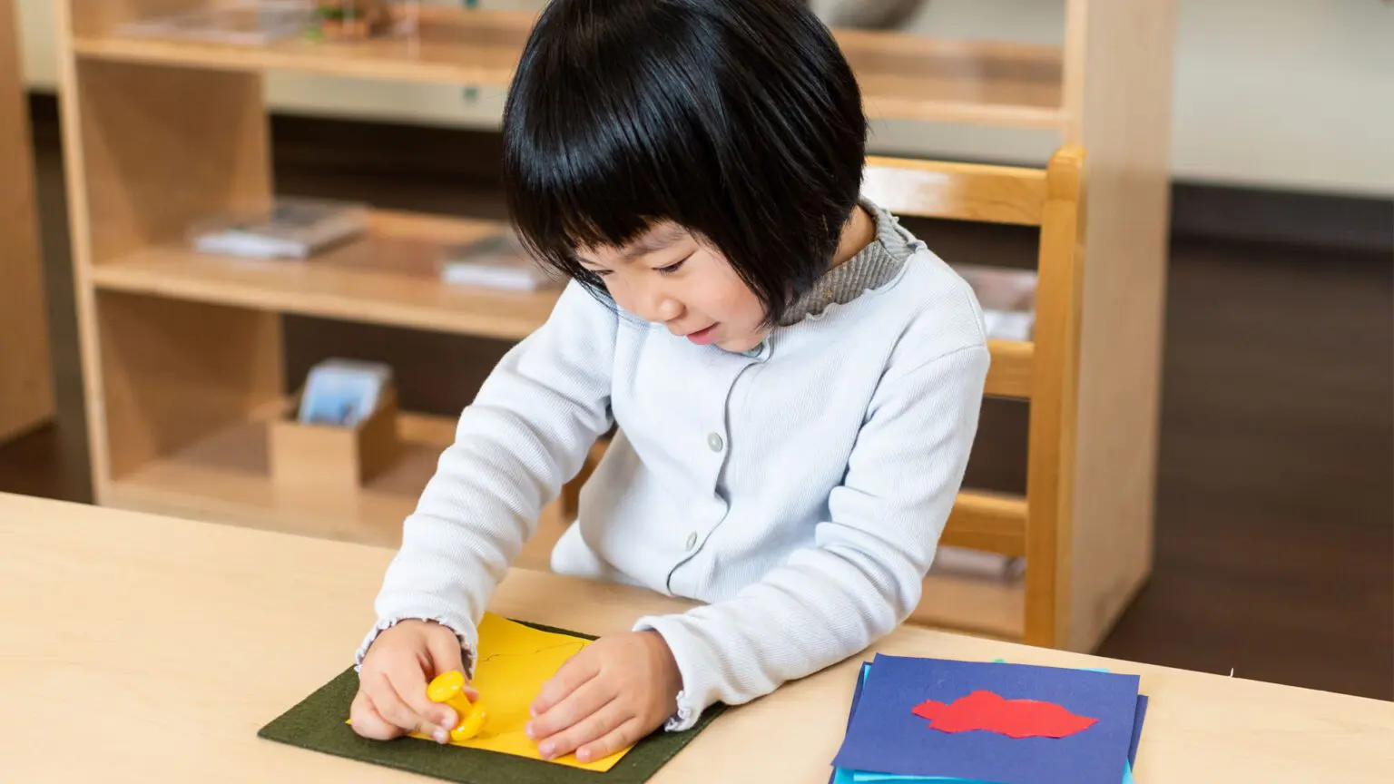 A young girl is writing on paper at the table.