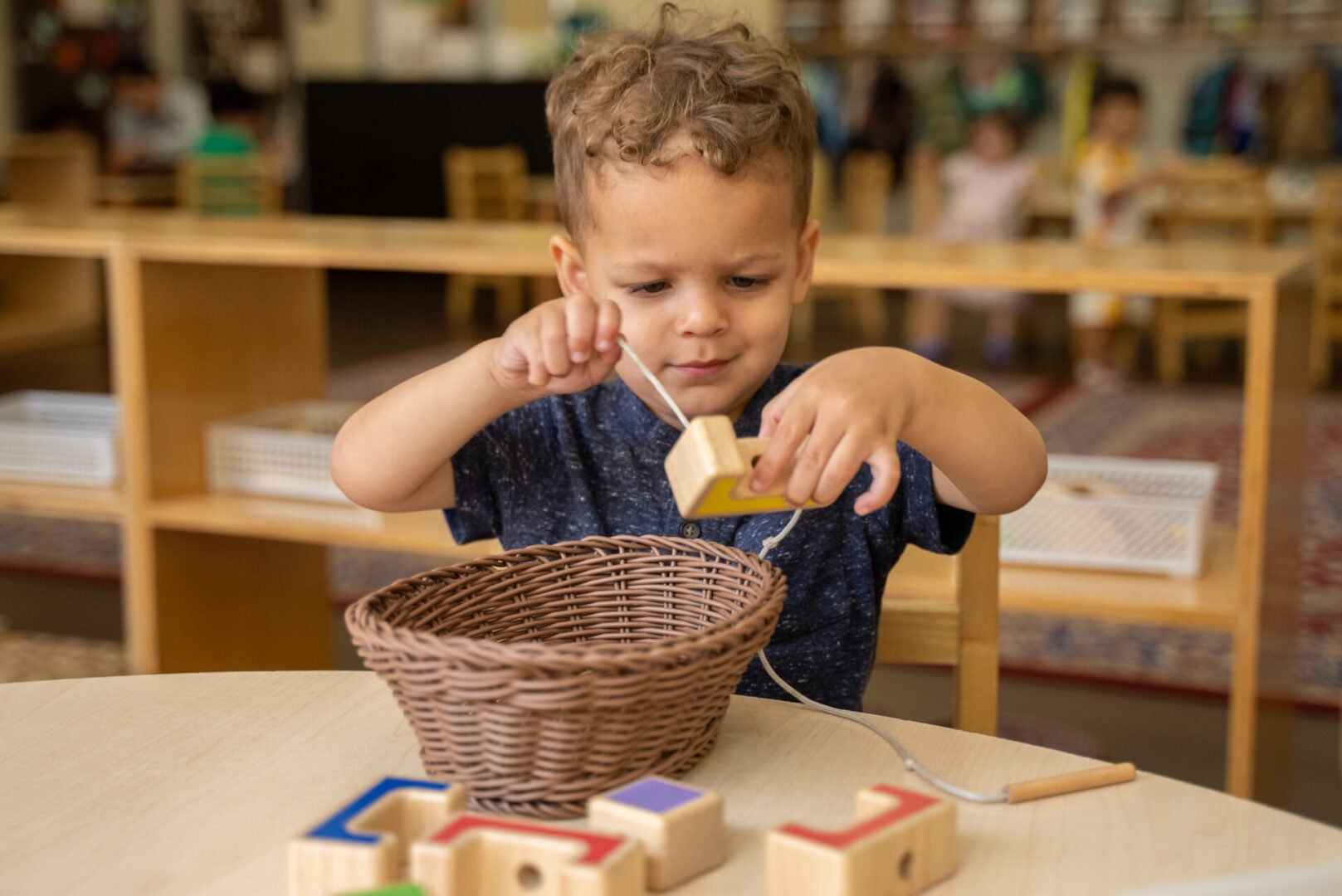 A young boy is playing with blocks at the table.