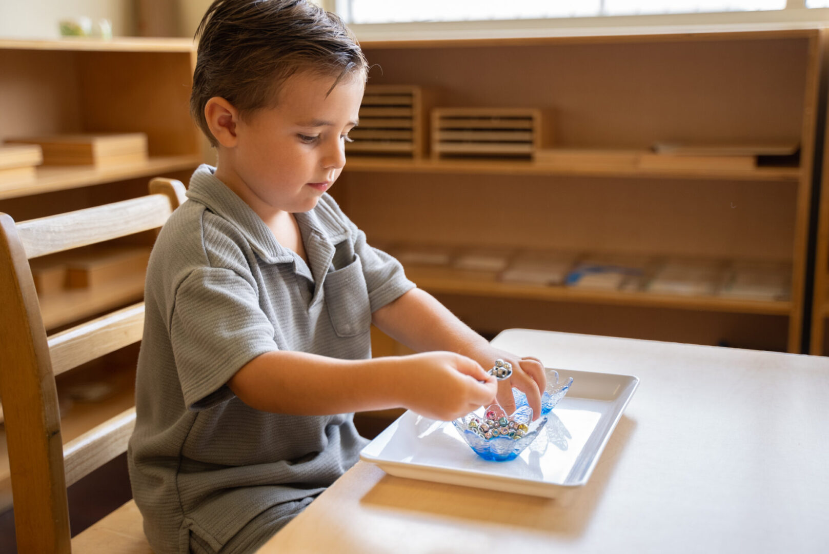 A boy is painting with blue paint on his hands.