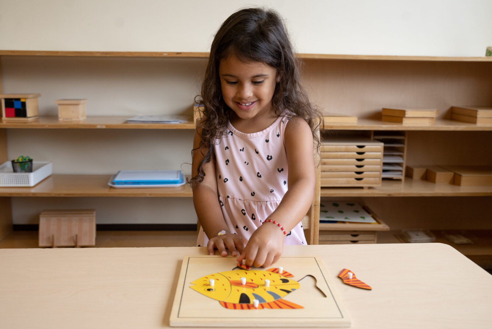 A little girl is cutting out shapes on the table.