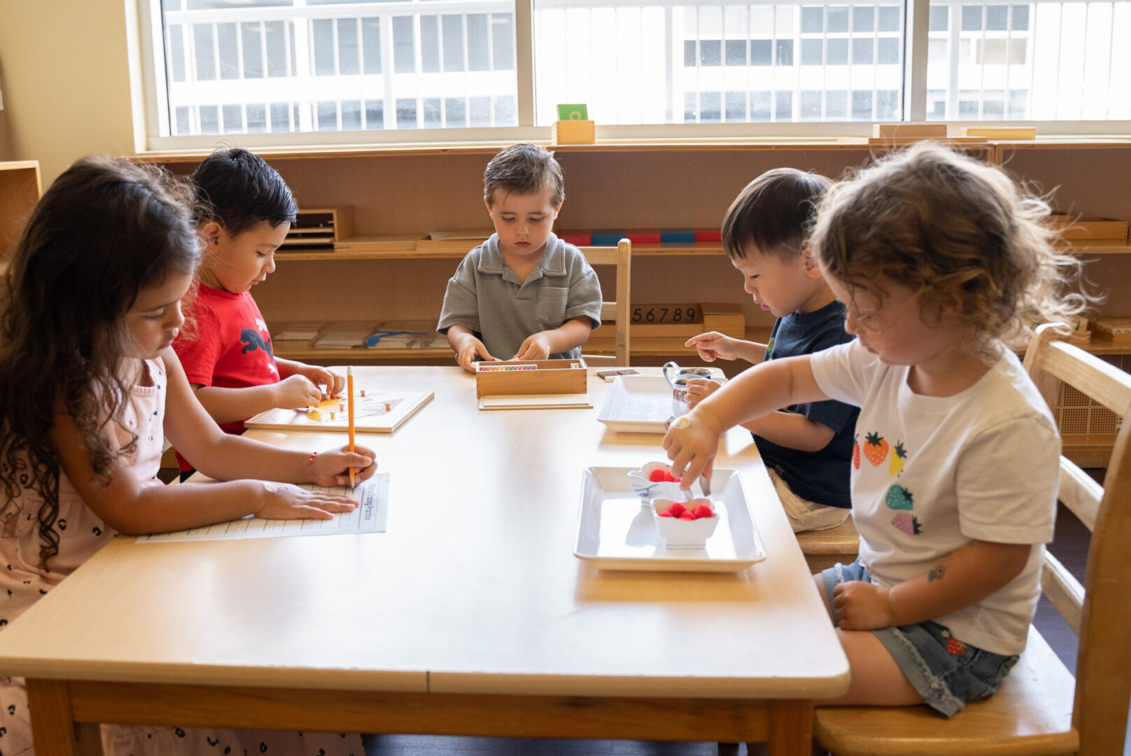 A group of children sitting at a table with pencils and paper.