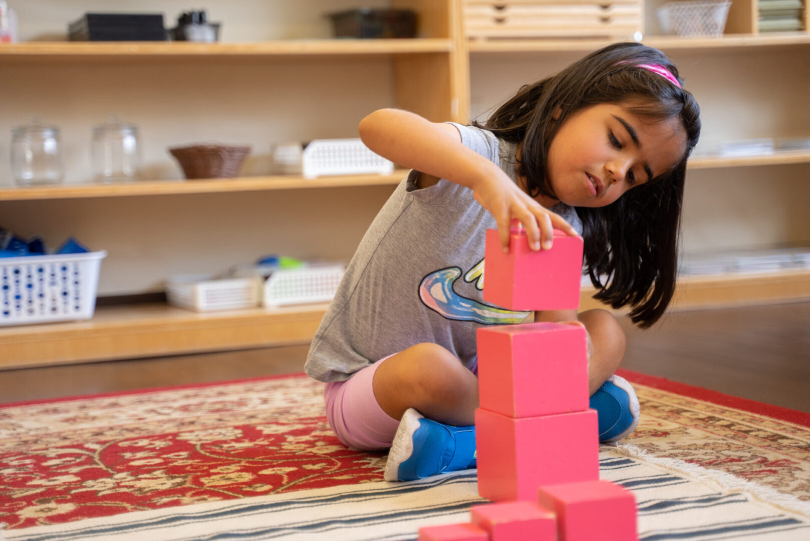 A little girl playing with blocks on the floor.