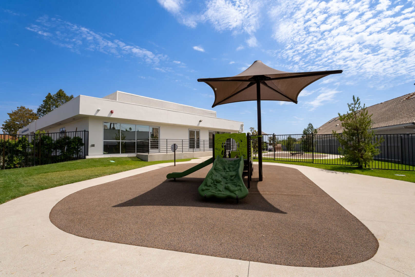 A playground with a slide and an umbrella.